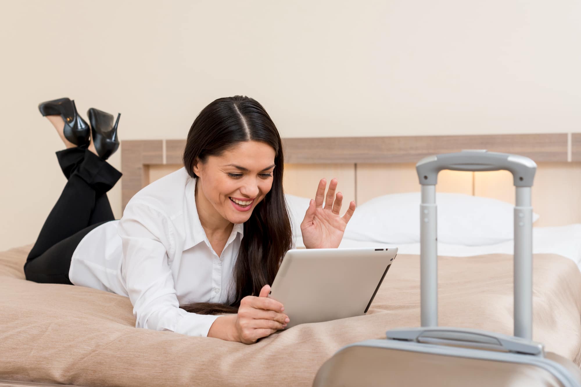 Woman lying on bed video calling on digital tablet